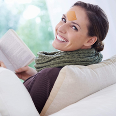 woman sitting reading smiling over shoulder wearing frownies wrinkle patches