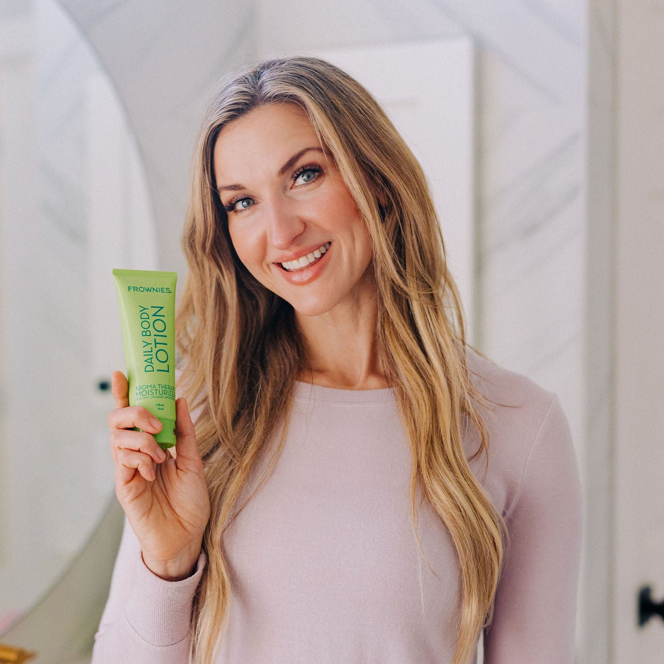 Frownies daily body lotion aroma therapy being held by a woman 