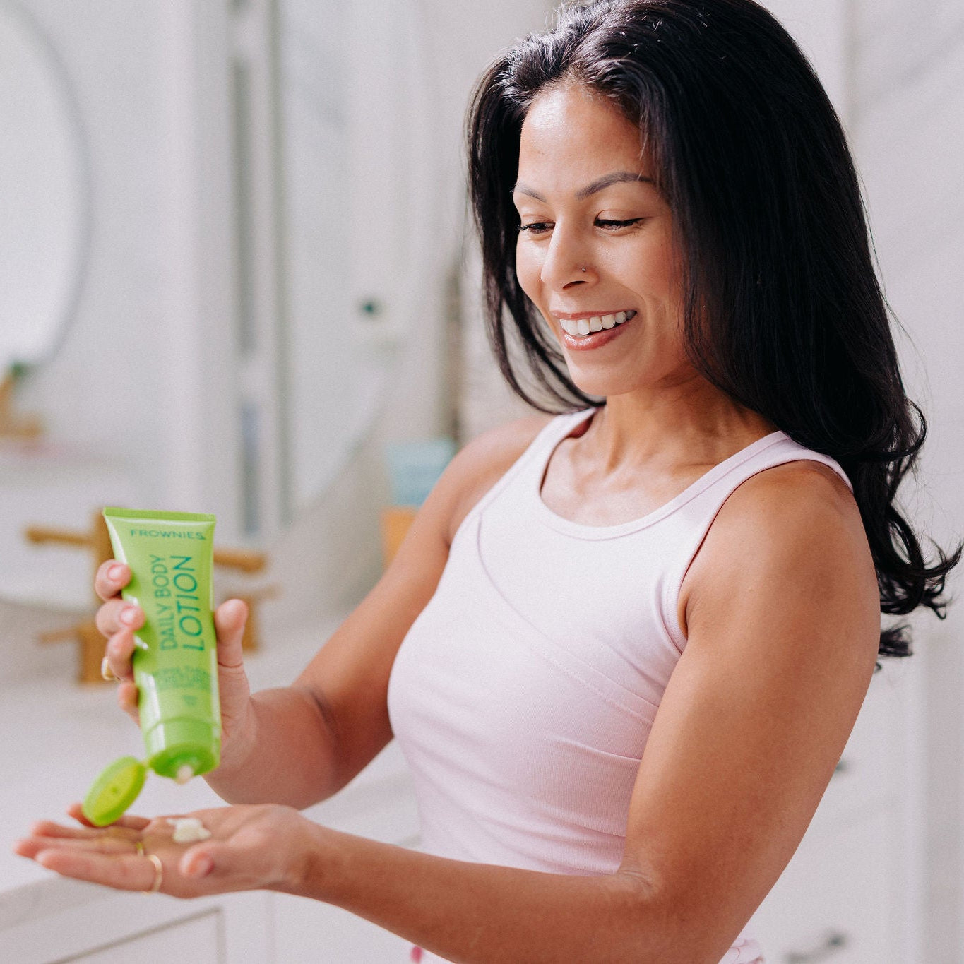Frownies daily body lotion being squeezed by a woman out onto her own hand 