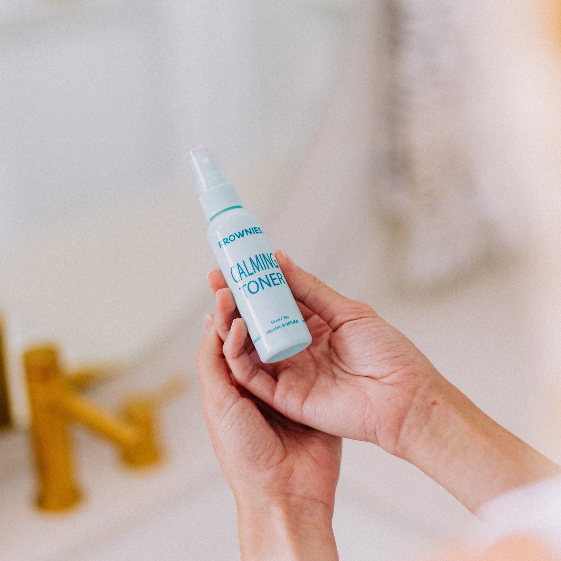 Frownies calming toner being held in hands 