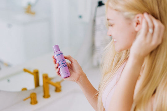woman holding frownies ph balancing face wash in her bathroom 