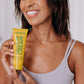 A woman with black hair shown holding the Frownies cellulite cream bottle in her hands and smiling