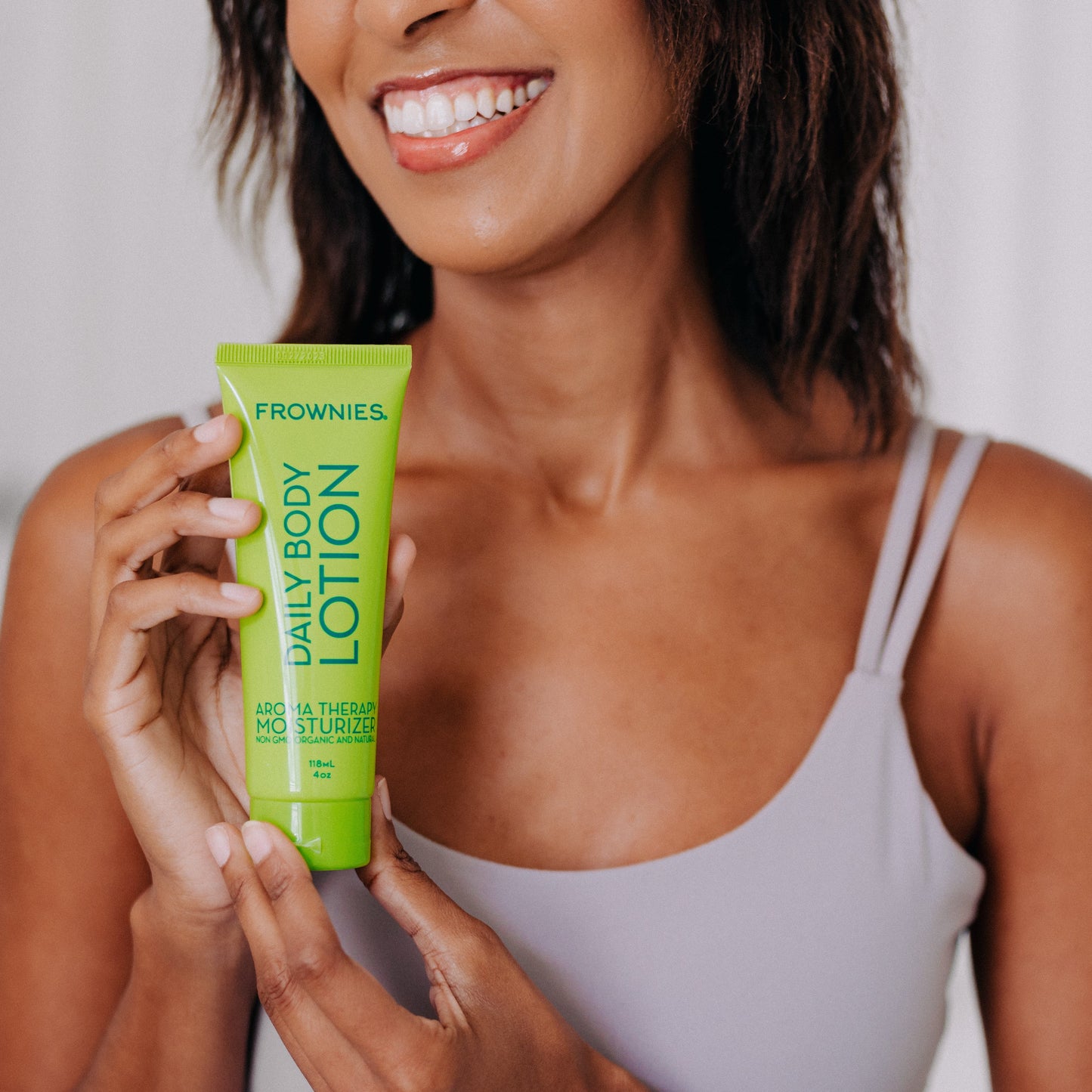 Frownies daily body lotion being held by a black woman 