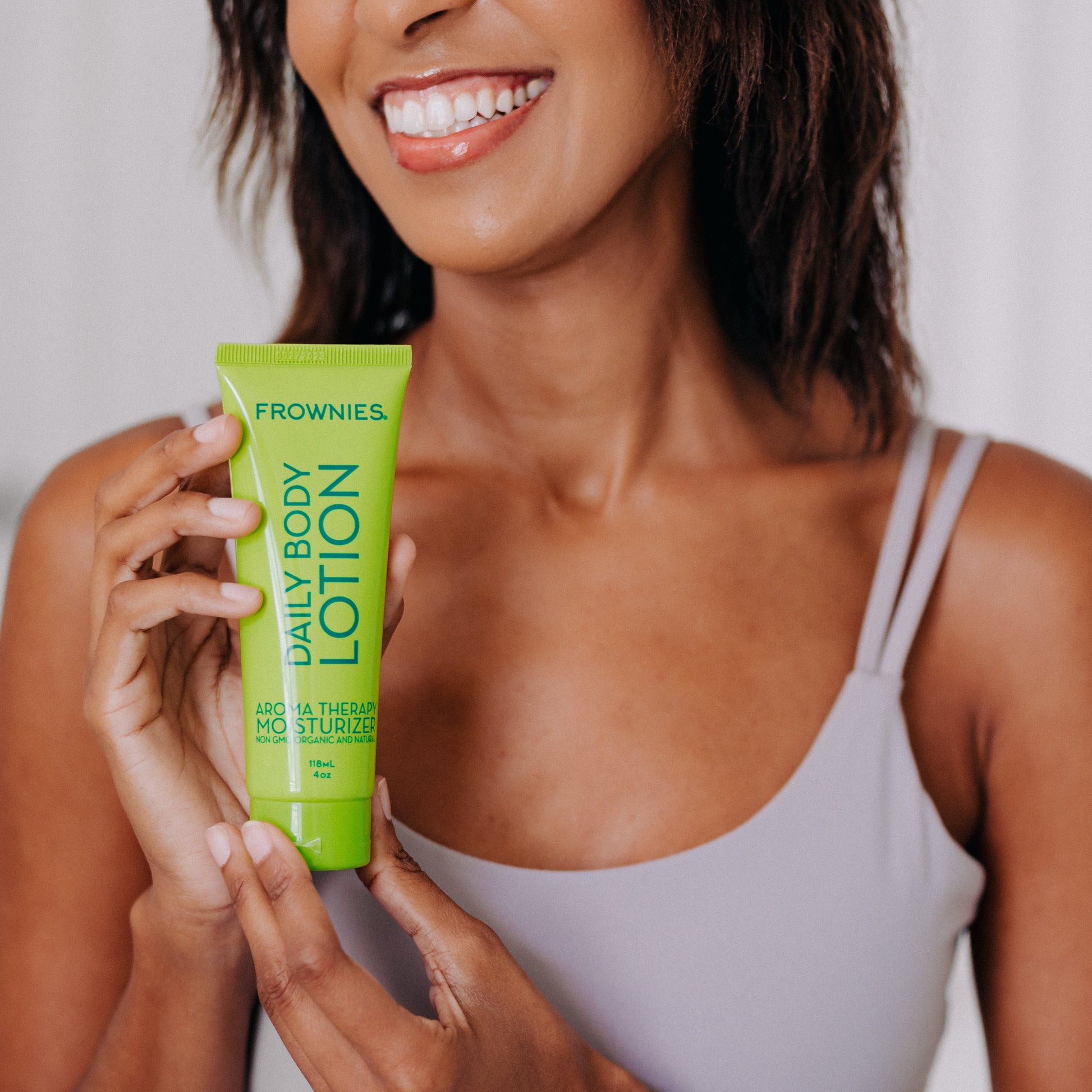 Frownies daily body lotion being held by a black woman 
