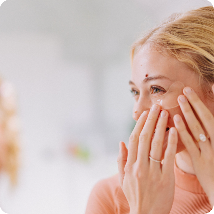 young blonde woman applying frownies under eye gels in her bathroom