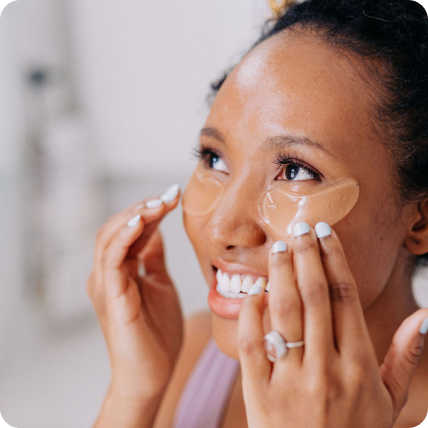 woman smiling as she places frownies under eye gels on her face