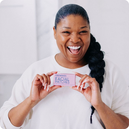 woman holding a box of frownies wrinkle patches to the camera
