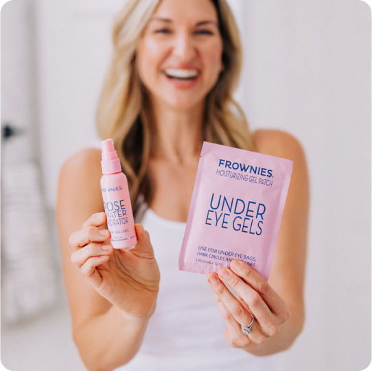woman smiling as she holds frownies rose water and under eye gels to the camera