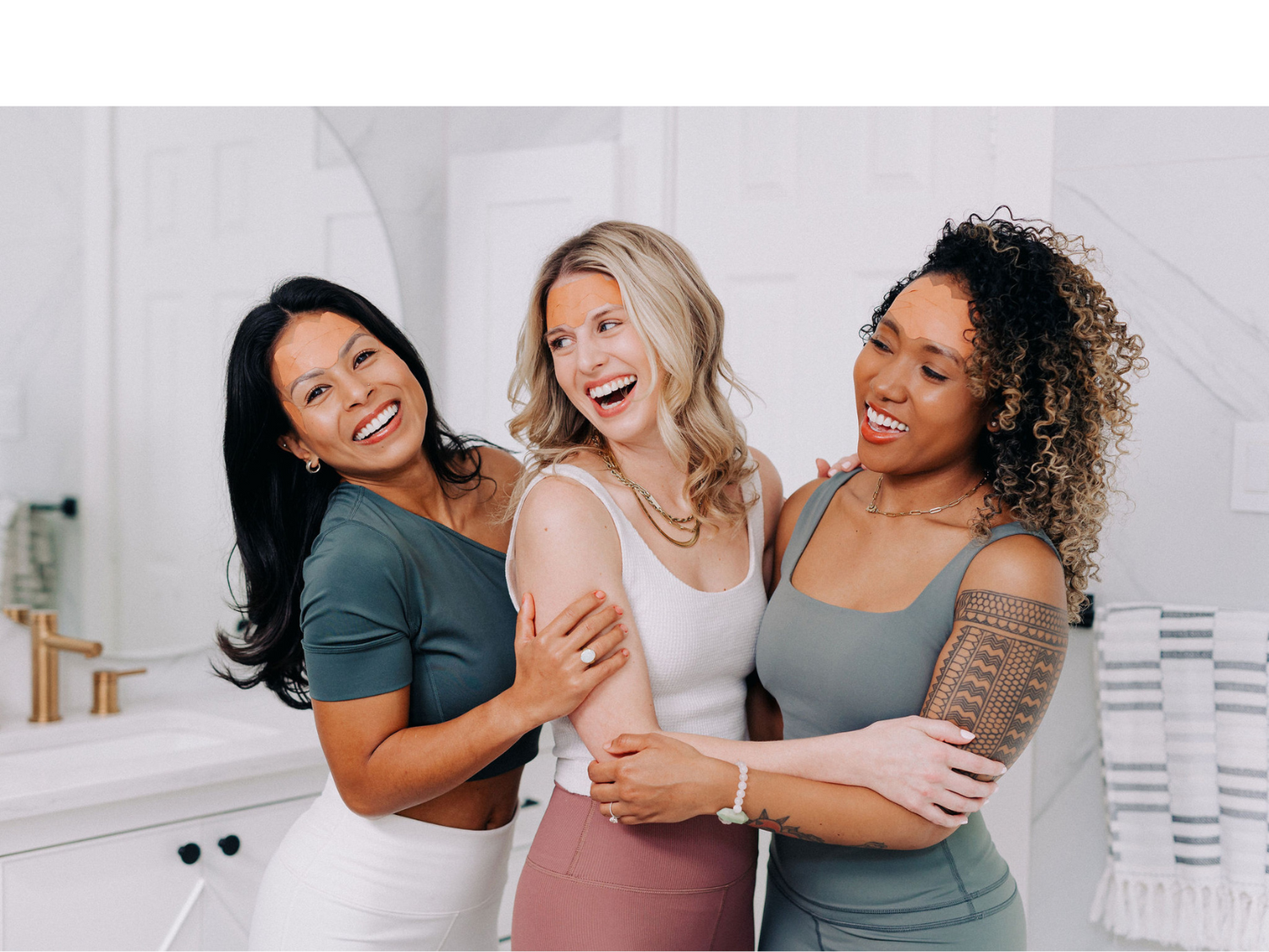 Three women hugging and wearing Frownies Facial Patches to smooth forehead wrinkles
