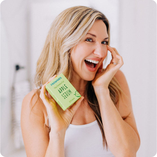 smiling woman applying frownies apply serum to smooth crows feet