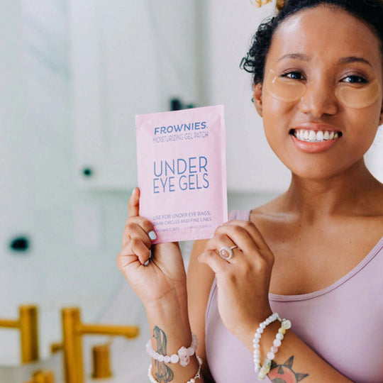 A smiling model holding the Frownies under eye gels package.