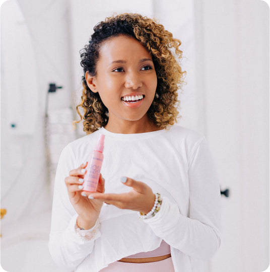 woman holding bottle of rose water spray