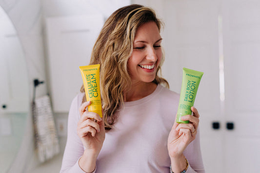 woman holding up lotion and cream that contain essential oils